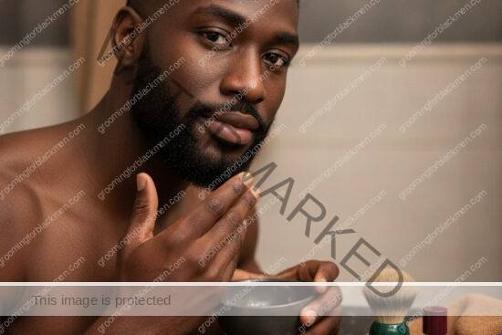 Black man in a premium grooming setting preparing aftershave care for bump-prone skin