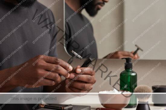 Black man with rich brown skin comparing shaving tools in a premium grooming routine