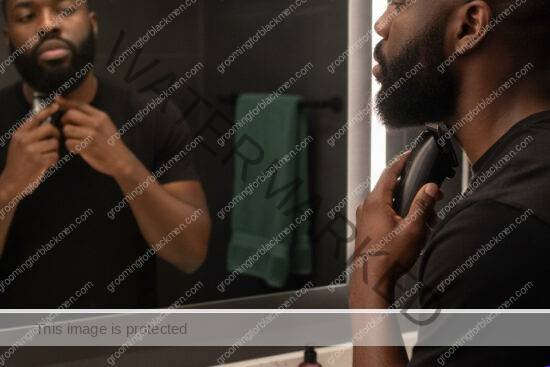 Black man with rich brown skin using a guarded trimmer for a careful grooming routine