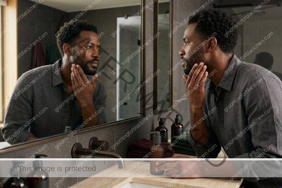 Black man with rich brown skin applying sunscreen before going outside